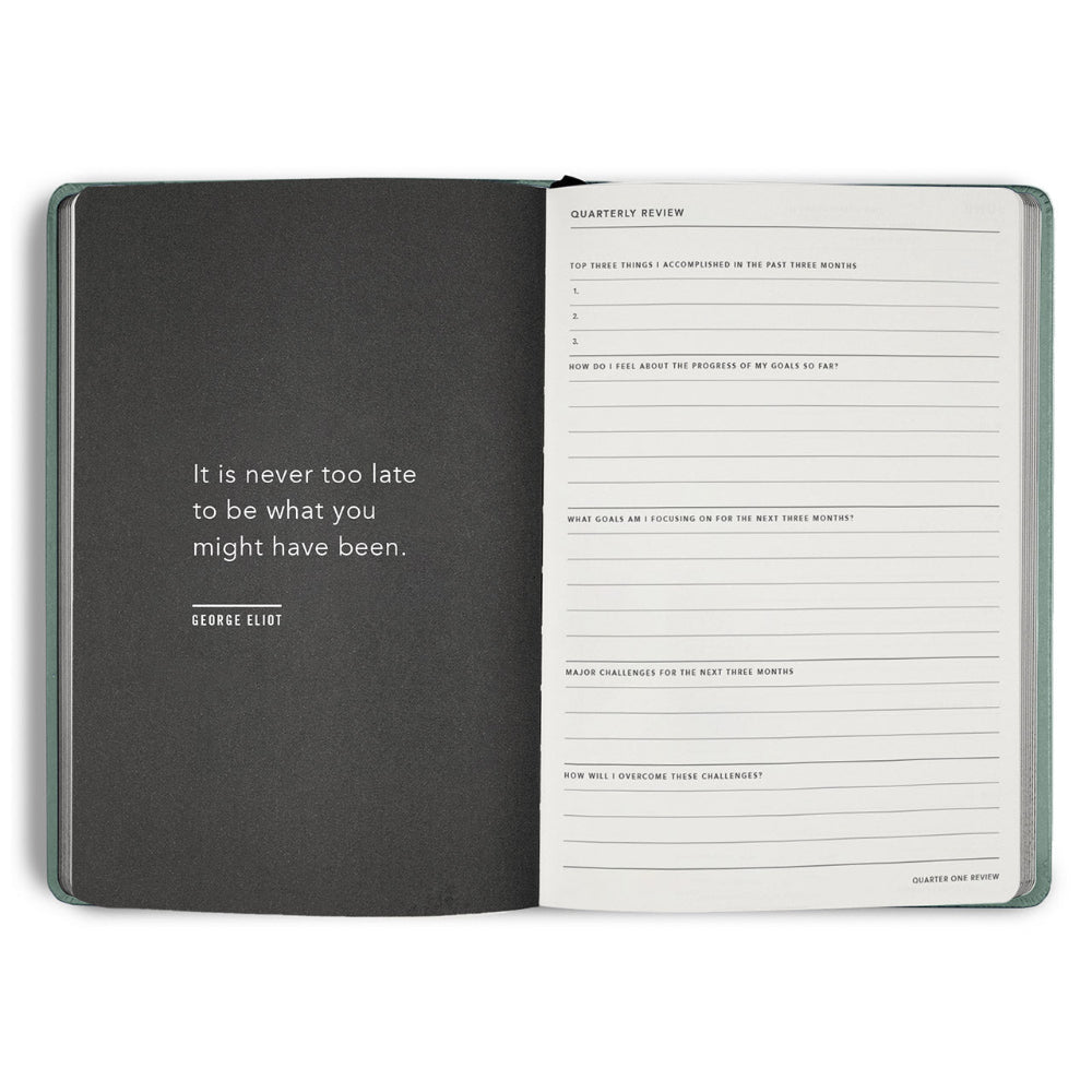 Open notebook with a quote by George Eliot on one page and a quarterly review form on the other, on a white background.