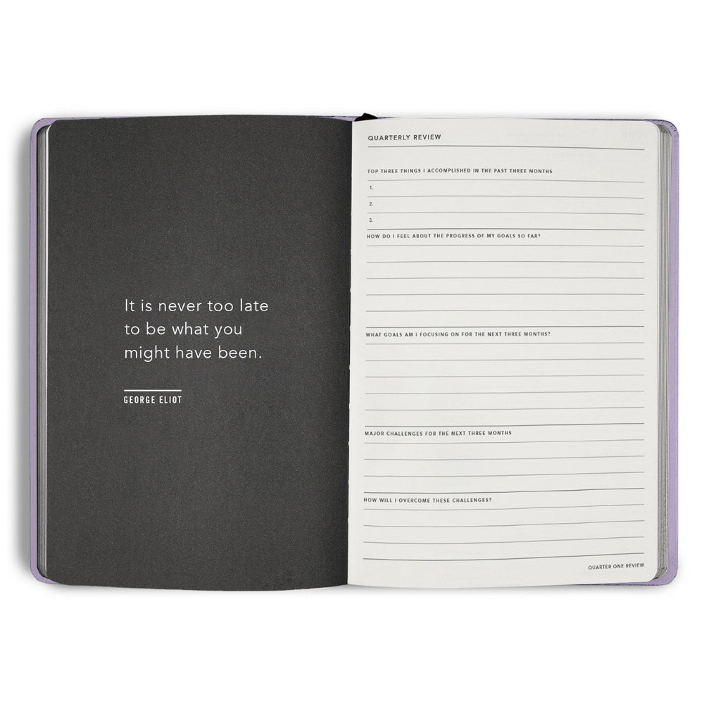 Open notebook with a quote by George Eliot on one page and a quarterly review form on the other, on a white background.